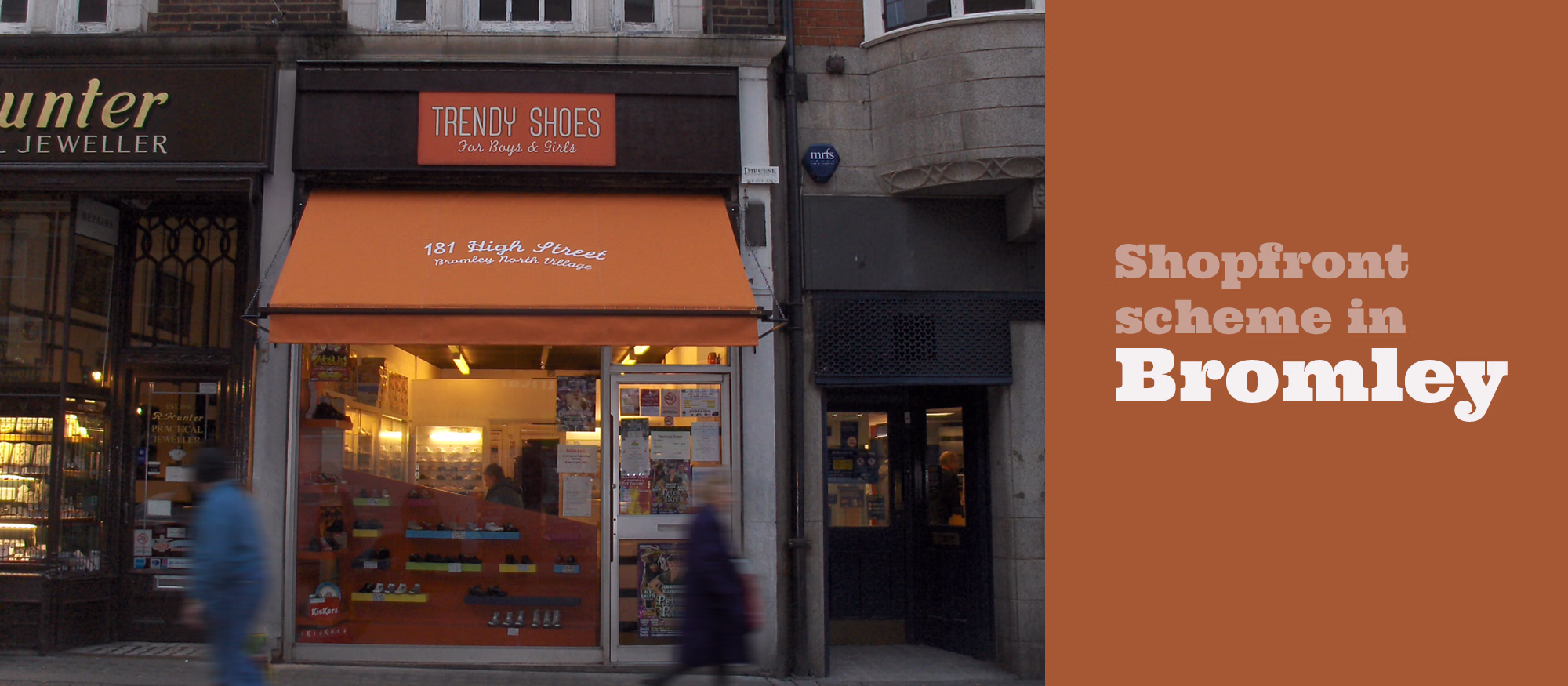 A street view shows a small shop with an orange awning and window display, the sign looks like a shoe tag with stitching on it, with two blurred people walking past. © This image is copyrighted. Not licensed for AI training, machine learning, or dataset creation.